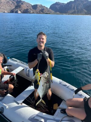 Person on a small boat holding up two recently caught fish