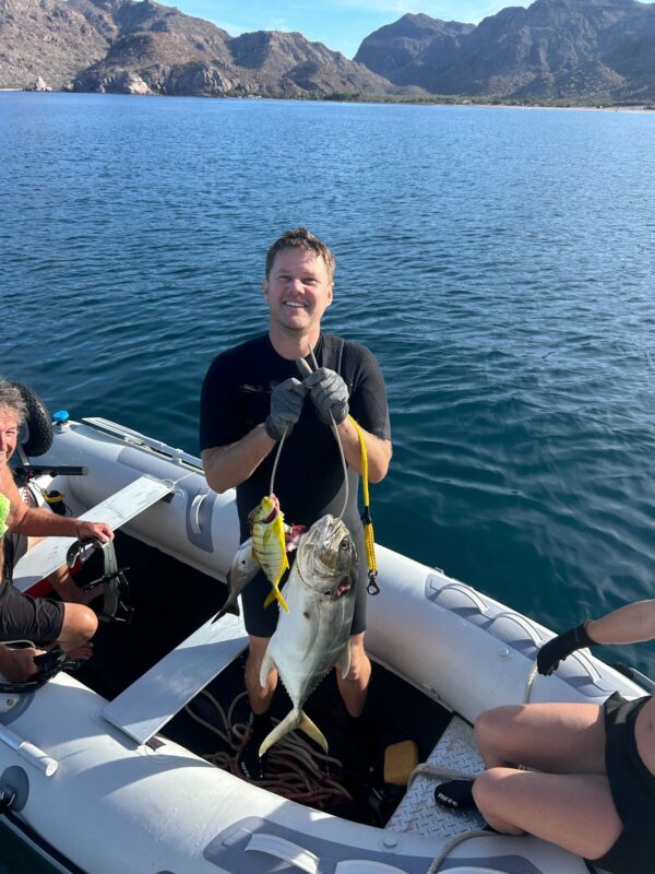 Person on a small boat holding up two recently caught fish