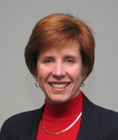 Woman with red hair wearing a red shirt and black blazer