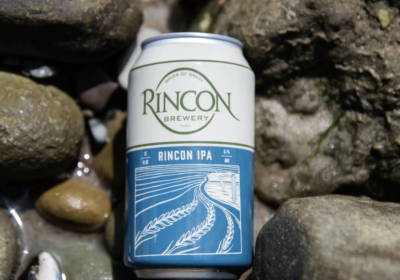 Rincon IPA beer set amongst rocks on seashore